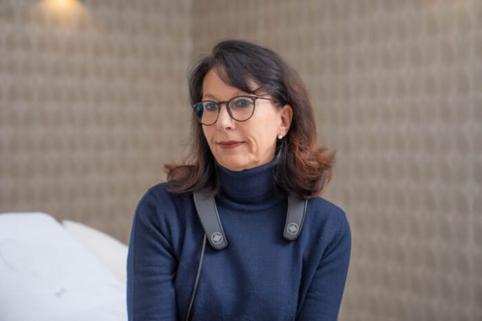 Eine Patientin sitzt auf der Behandlungsliege und trägt das Impulse Messgerät um den Nacken