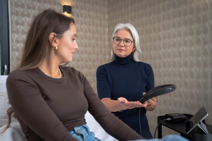 Die Kosmetikerin reicht der Kundin das Messgerät